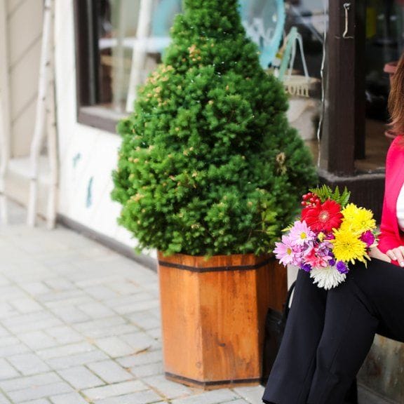 Smiling woman in red blazer with bouquet of flowers on her lap